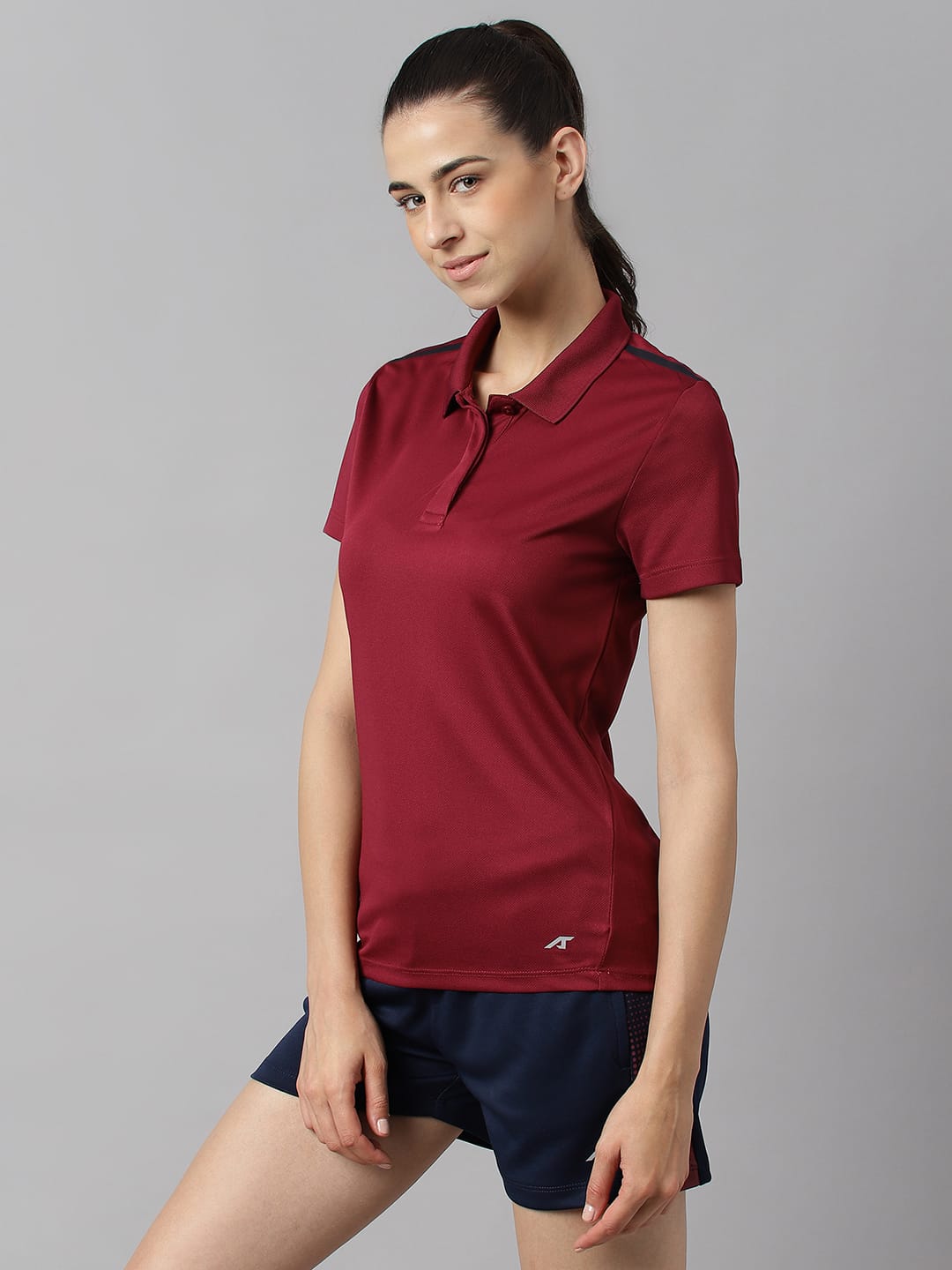 Alcis red plum training polo T-shirt for women made with breathable 100% polyester fabric for workouts.