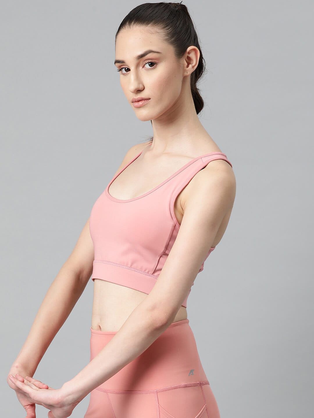 Women's pink slim fit sports bra with round neck and moisture-wicking fabric for gym, yoga and training by Alcis.